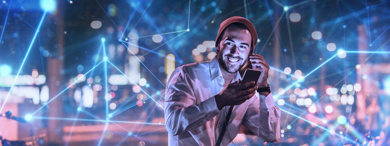 一個人正在微笑，他一隻手拿著手機，另一隻手正在調整耳機