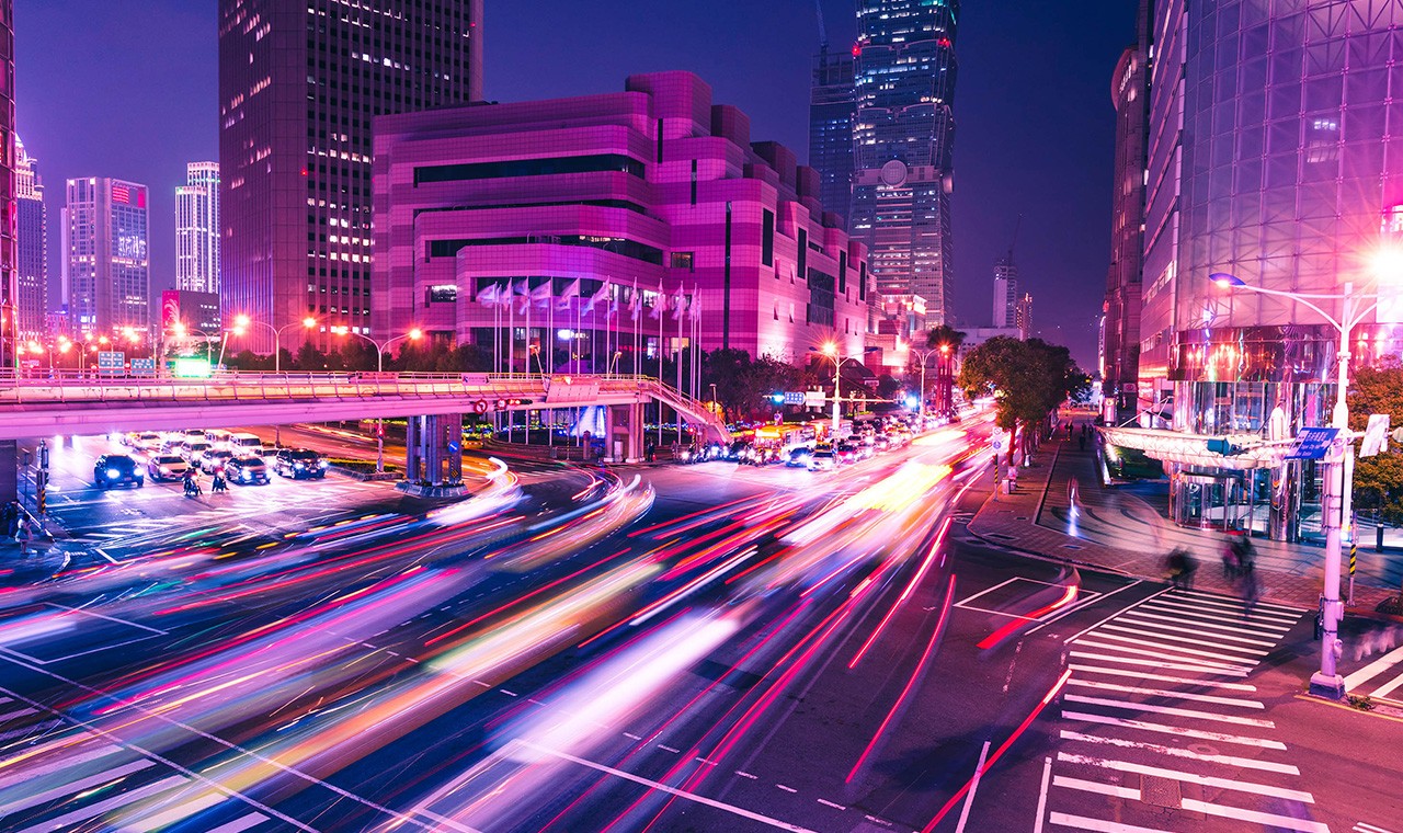 燈火通明的摩天大樓夜景，伴隨著車燈光束