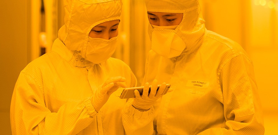 兩名穿著無塵室套裝的 Fab 同事正在看手機